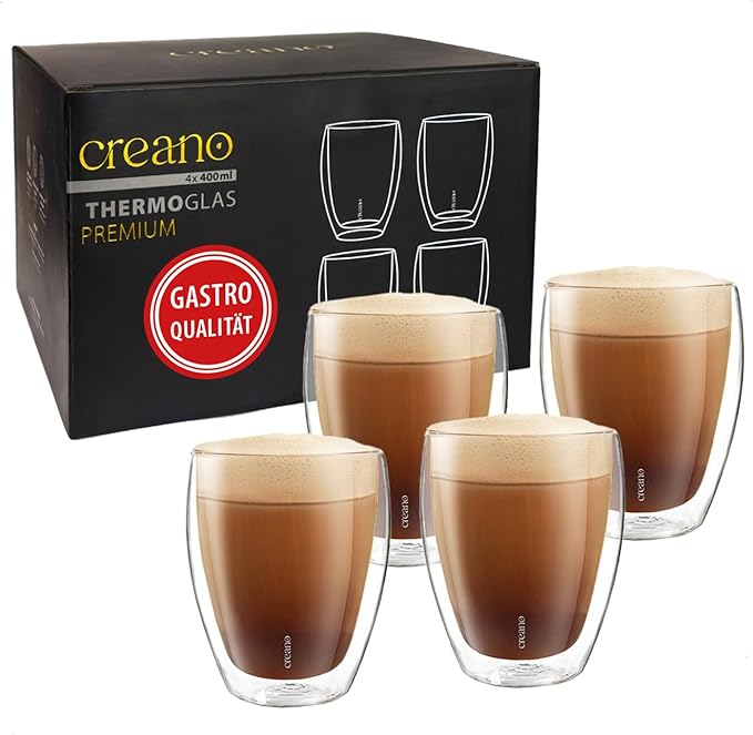 Vier doppelwandige Creano Thermogläser mit Cappuccino neben schwarzer Verpackung